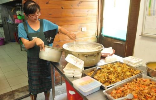 南投縣⽣活重建協會為獨居老⼈送餐⻑達18年，圖為⼯作⼈員打菜的情形。（記者柏 原季／攝影）