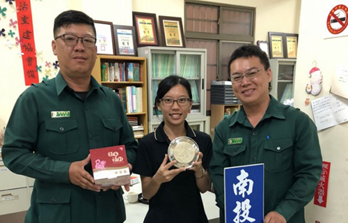 綠衣天使郵遞愛心！江建龍（右）、楊榮峰（左）冒著大雨將新便當盒送到國姓鄉，由南投縣生活重建協會社工人員（中）代表接受。（南投縣生活重建協會提供）